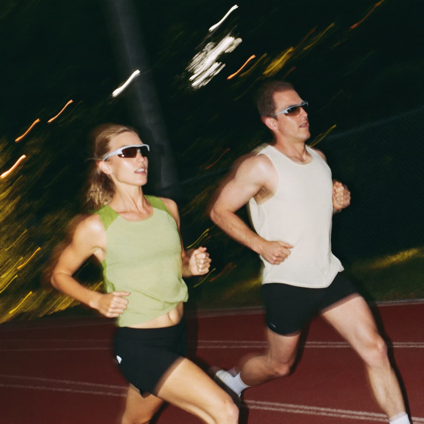 Two runners mid-stride side by side on an athletics track, caught with motion blur